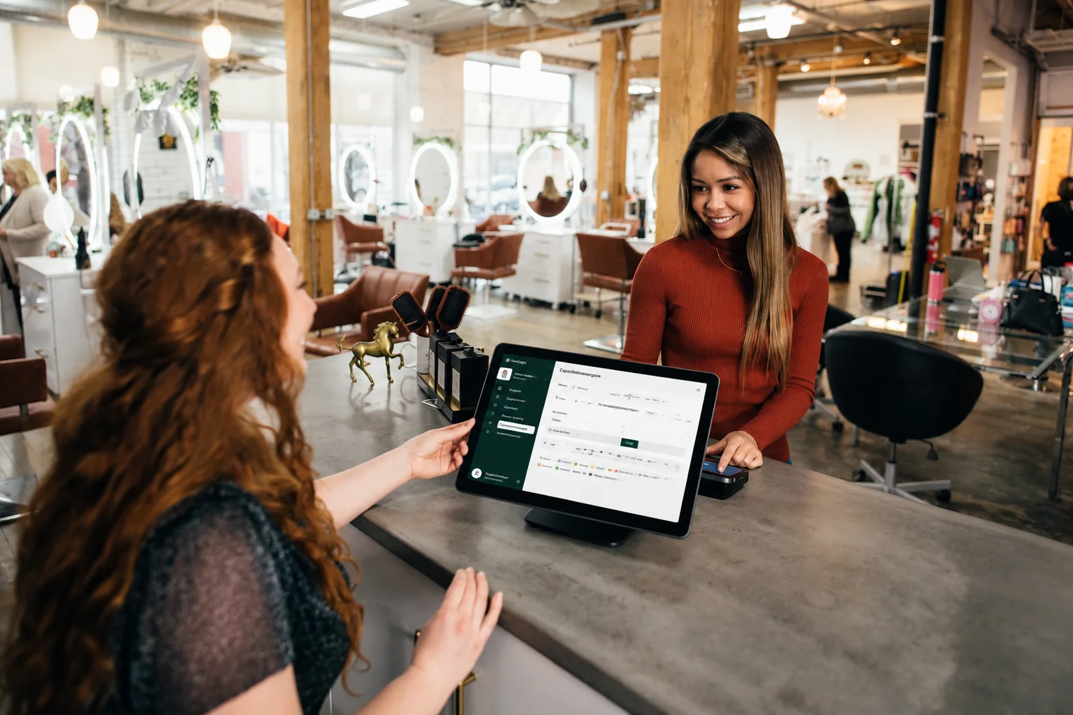 Medewerker aan de balie van een salon toont de capaciteitsweergave van PlanLogic op een tablet aan een klant